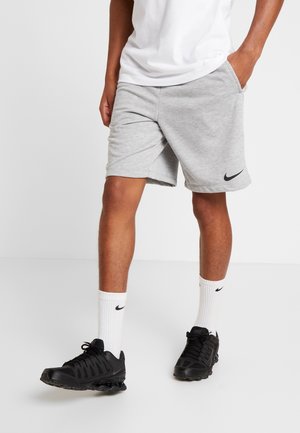 Pantalones cortos deportivos grises con bolsillos, confeccionados con una tela suave, que presentan un logo negro de Nike. Llevados con zapatillas negras y calcetines blancos con el logo de Nike.