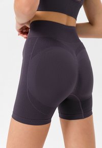 Dunkelviolette Sportshorts mit hohem Bund, die über strukturierte Einsätze und ein enganliegendes Design verfügen, um Komfort und Flexibilität zu bieten.