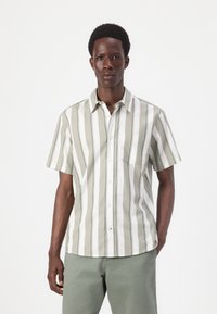 Chemise à manches courtes à boutons avec des rayures vert clair et blanches, dotée d'une poche et d'une coupe décontractée, en tissu de coton texturé.