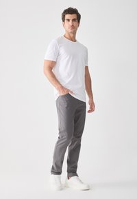 Camiseta blanca de manga corta combinada con pantalones ajustados grises y zapatillas blancas. Diseño simple, tejido ligero y corte recto.