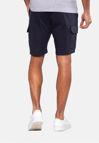 Navy cargo shorts in cotton blend, featuring side pockets and a relaxed fit. Paired with white sneakers.