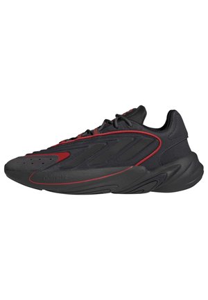 Czarny i ciemnoczerwony sportowy sneaker z wiązaniem na sznurówki, fakturowaną podeszwą i smukłą sylwetką.