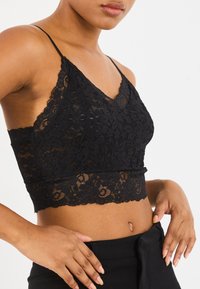 Crna čipkasta bralette s V-izrezom, podesivim trakama, cvjetnim uzorkom, skraćenim dizajnom i valovitim rubovima.