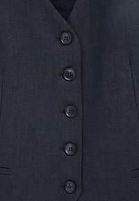 Blazer gris oscuro con cinco botones negros alineados verticalmente en el centro delantero, tejido texturizado y dos bolsillos delanteros.