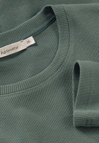 Grön randig bomullströja med rund halsringning och korta ärmar, försedd med en etikett med varumärkesnamn och storlek sydd inuti.