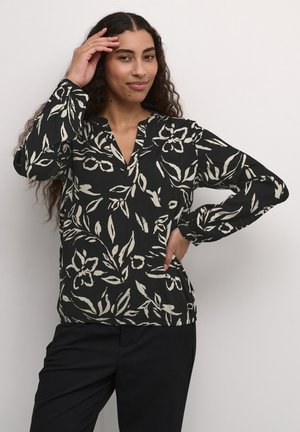 Blouse noire à manches longues avec un col en V, ornée d'un imprimé floral crème. Coupe ample avec un tissu texturé et des manches élastiquées.