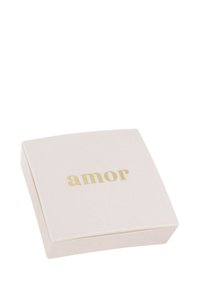 Kwadratowe, miękkoróżowe pudełko o matowym wykończeniu, z napisem "amor" w złotym drukowanym kroju. Wieczko ma delikatnie zaokrąglone krawędzie.