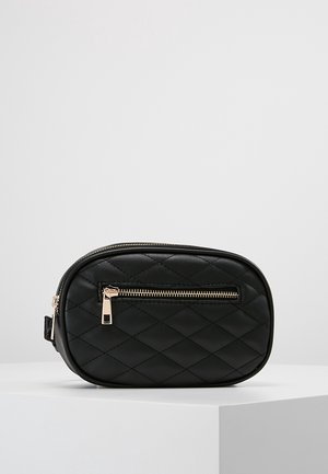 Czarna pikowana owalna saszetka z złotą kieszenią na suwak z przodu, głównym zamkiem błyskawicznym i gładką teksturą skóry na białej powierzchni.