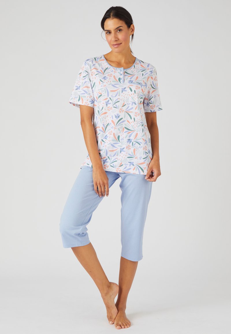 Blusa de manga corta floral en colores pastel con escote redondo y detalle de botones, combinada con pantalones cortos de color azul claro en tela suave.