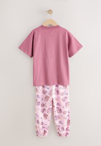 Różowy bawełniany T-shirt z krótkimi rękawami, zestawiony z jasnoróżowymi spodniami dresowymi z kolorowymi wzorami kreskówkowymi i elastycznymi ściągaczami.