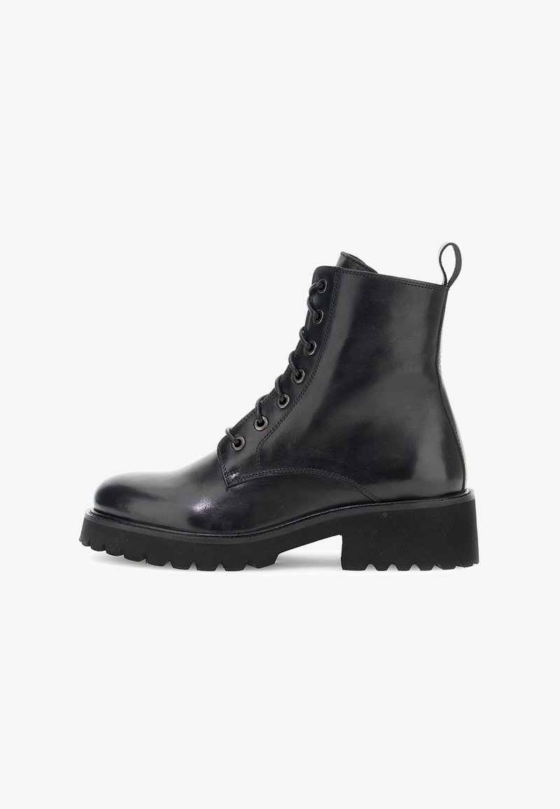Botte cheville en cuir noir avec lacets à l'avant, semelle épaisse et robuste, et une languette à l'arrière, présentée de côté sur un fond blanc.