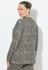 Langärmliges Oberteil mit einem schwarz-beigen Leopardenmuster. Verfügt über einen lockeren Schnitt, einen runden Halsausschnitt und eine glatte, weiche Stofftextur.