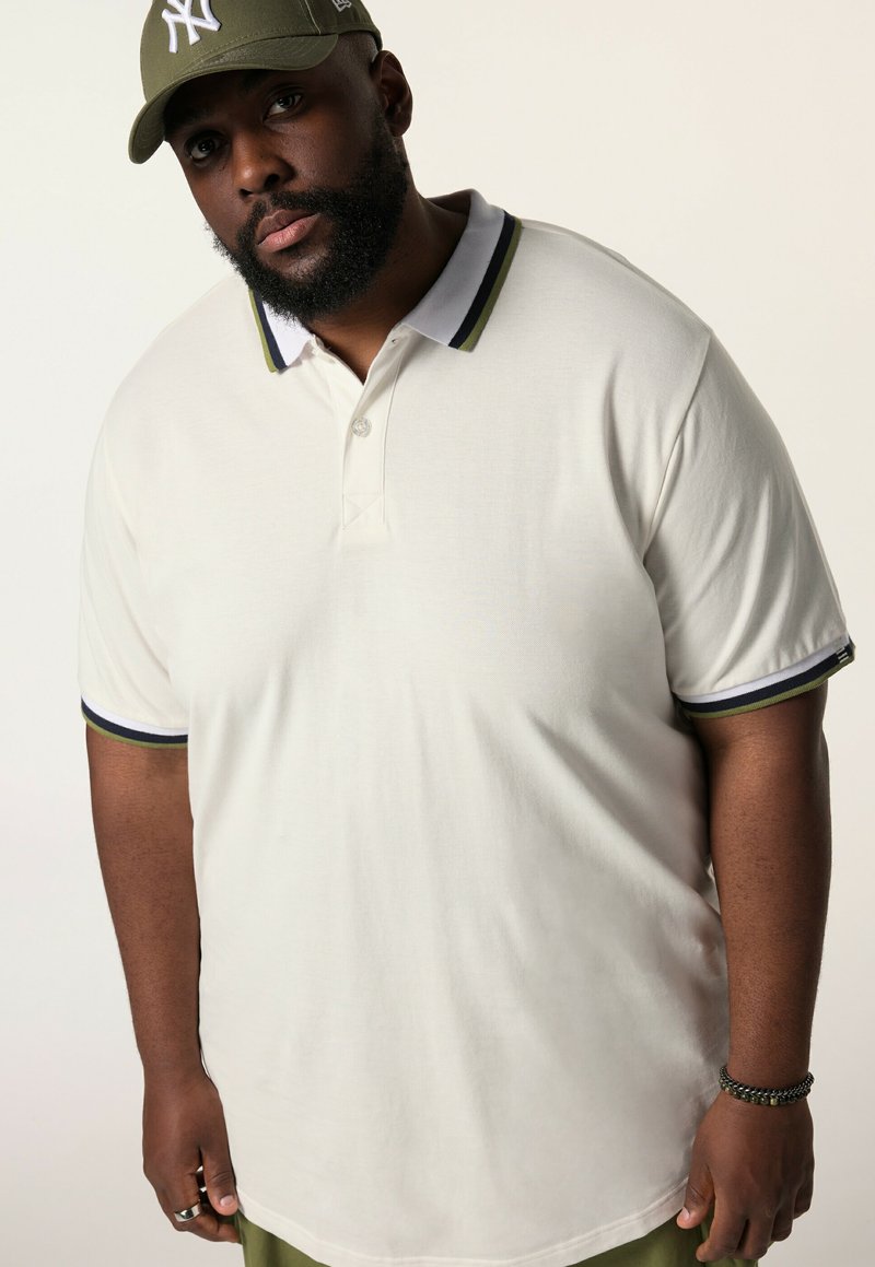 Krämfärgad polo t-shirt med en treknappsknäppning, kontrasterande marinblå och olivgröna ränder på kragen och ärmarna. Slätt bomullstyg.