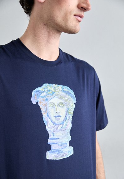 T-shirt en coton marine présentant une illustration multicolore d'une tête de sculpture classique avec des cheveux détaillés et le mot "VERSACE" à la base.