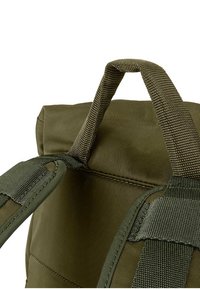 Olijfgroene rugzak van gepaddede stof, met verstelbare schouderbanden, versterkte stiksels, een handvat aan de bovenkant en een gestructureerde afwerking op de banden.