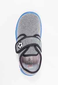 Szare buty z tkaniny z niebieską podeszwą, wyposażone w czujny pasek na rzep i motyw piłki nożnej. Widoczna etykieta wewnętrzna, zawierająca informacje o rozmiarze i pielęgnacji.