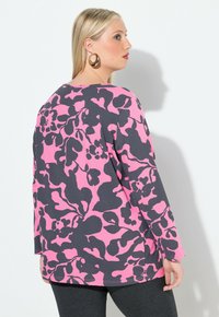 Langsleeve top in grijs met een roze abstract bloemenpatroon. Zachte stof met een relaxte pasvorm en een ronde halslijn. Zijsplitten aan de zoom.