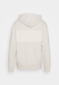 Haut de sweat à capuche gris clair avec un panneau horizontal blanc au dos, en tissu mélangé coton, capuche ajustable avec cordon de serrage et poignets côtelés.