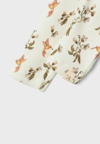 Geribbelde stof in off-white met kleurrijke bloem- en kolibri-patronen en een klein label aan de rand.