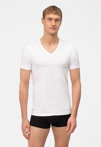Witte katoenen v-hals t-shirt met korte mouwen, aansluitend ontwerp, gladde textuur en een effen voorkant, gedragen met zwarte boxershorts.