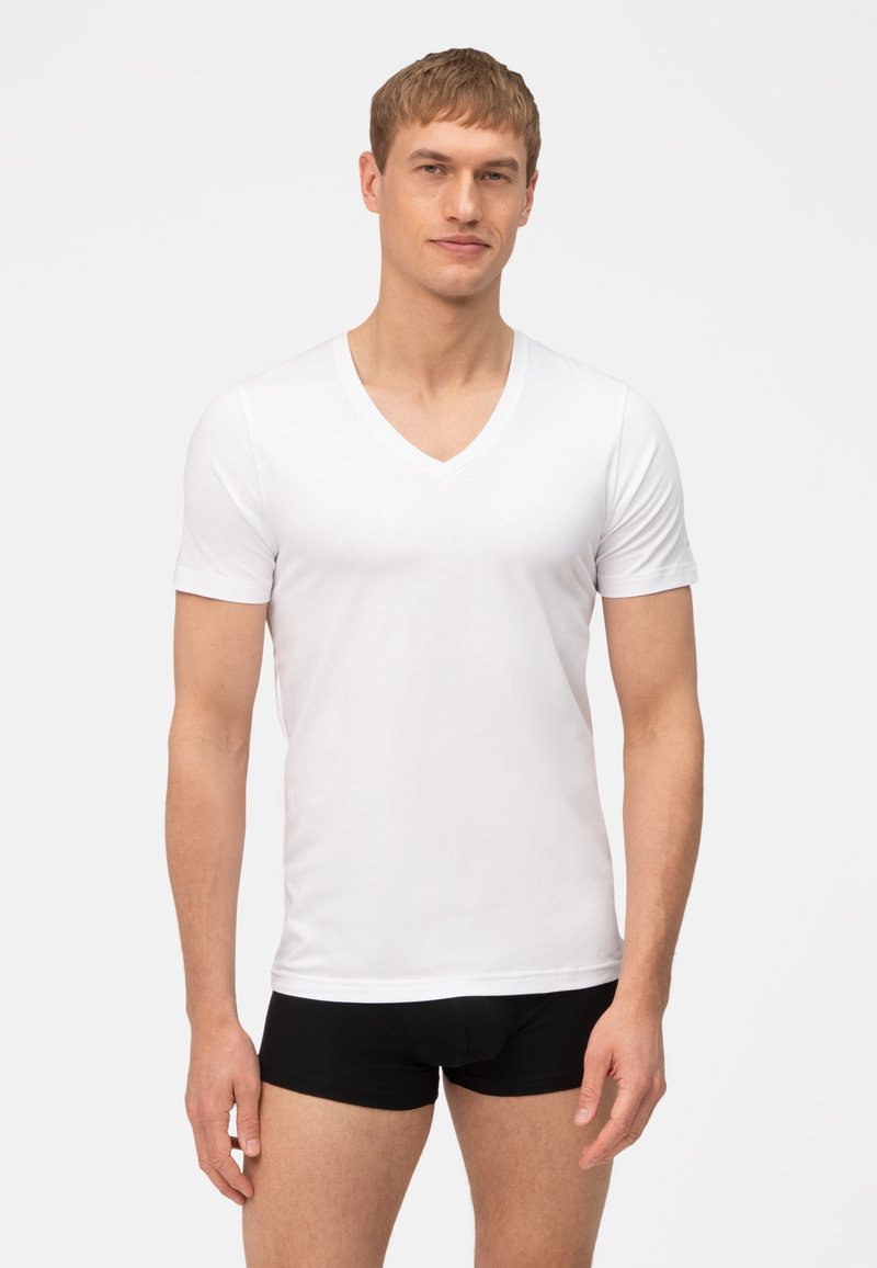 Witte katoenen v-hals t-shirt met korte mouwen, aansluitend ontwerp, gladde textuur en een effen voorkant, gedragen met zwarte boxershorts.