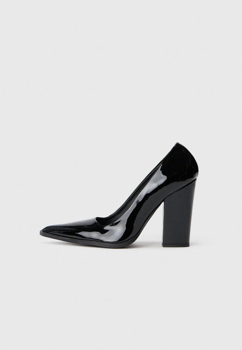 Pantofii cu toc înalt din piele patent neagră, cu vârf ascuțit și toc masiv, având o suprafață netedă și lucioasă, precum și un design elegant.