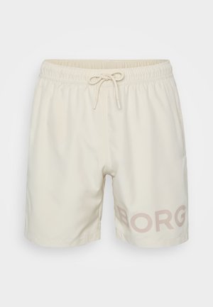 Jasno beżowe szorty kąpielowe z elastycznym pasem, sznurkiem do regulacji oraz subtelnym nadrukiem "BORG" w różowym na dolnym lewym boku. Gładka faktura materiału.