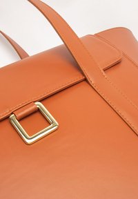 Leren handtas in oranje met een rechthoekige vorm. Voorzien van een gouden gesp en een platte, gestructureerde klep met contrasterende stiksels.