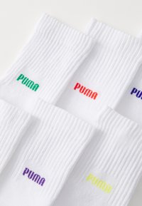 Weiße gerippte Socken mit bunten bestickten "PUMA"-Logos in Grün, Rot, Lila und Gelb. Vier Paare für die Präsentation angeordnet.