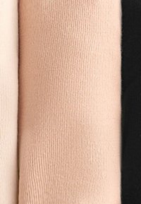 Drie opgerolde stofmonsters in nude en zwarte kleuren, die verschillende texturen en tinten tonen, naast elkaar gerangschikt.