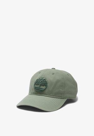 Green cotton cap featuring an embroidered tree logo on the front, curved brim, six panel design, and ventilation eyelets.