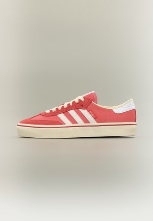 Κόκκινο και λευκό Adidas Samba χαμηλό παπούτσι με εκρού σόλα και κορδόνια, εμφανιζόμενο σε προφίλ σε ουδέτερο φόντο.