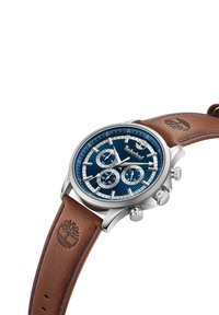 Orologio cronografo con quadrante blu a righe, lavorazioni in argento e cinturino in pelle marrone con cuciture blu e logo impresso.