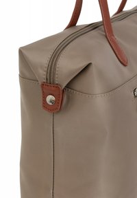 Borsa in nylon beige con dettagli in pelle marrone, dotata di chiusura con zip e due manici robusti. Texture liscia con rifiniture di cucitura ordinate.