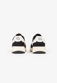 Zapatillas en blanco y negro con un upper texturizado, forma redondeada, cuello acolchado y detalle del logo en el talón, con suela de goma.