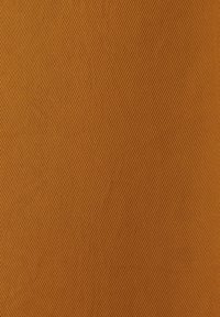 Gros plan d’un tissu avec une fine texture côtelée diagonale de couleur brun chaud et un motif uniforme et cohérent.