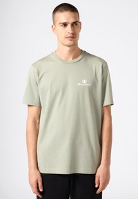 Camiseta de manga corta de color verde claro, hecha de algodón, con un pequeño logo blanco en el lado izquierdo del pecho y un diseño clásico de cuello redondo.