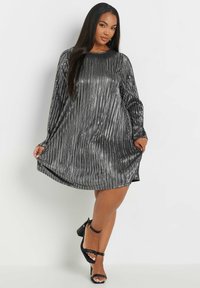 Kortärmad, knälång klänning i skimrande svart tyg med vertikala silverränder. Har en rund halsringning och en lös passform.