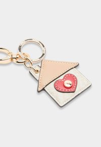 Portachiavi con un design a forma di casa nei colori beige e crema, con un accento a forma di cuore rosso. Realizzato in materiale simile alla pelle, con cuciture dettagliate e accessori metallici.