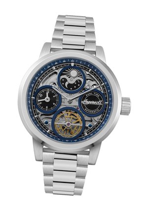 Montre automatique avec un bracelet en acier inoxydable, cadran noir et bleu, double fuseau horaire, engrenages visibles et accents dorés.