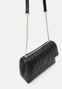 Czarna pikowana torebka ze skóry z złotym łańcuszkowym paskiem i skórzanym uchwytem na ramię. Ma prostokątny kształt i gładką fakturę.