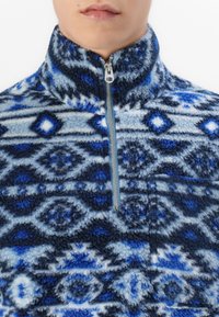 Fleece pullover i nuancer af blå med geometriske mønstre. Har en høj krave, halv lynlås og tekstureret, blødt stof.