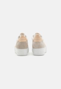 Des baskets en daim beige et rose clair avec une semelle en caoutchouc blanche. Présentent un talon arrière texturé et une marque au dos. Design à bout rond.