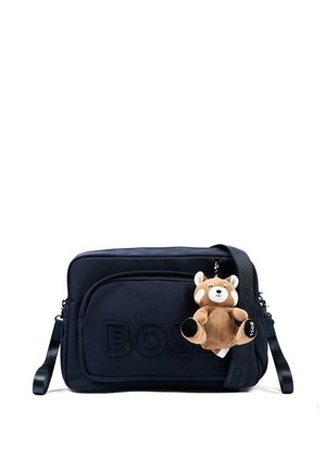 Borsa a tracolla nera BOSS con tasca frontale e portachiavi a forma di orsetto marrone peluche attaccato alla tracolla.
