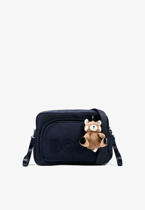 Sac bandoulière BOSS noir avec poche avant et porte-clés nounours en peluche marron fixé à la sangle.