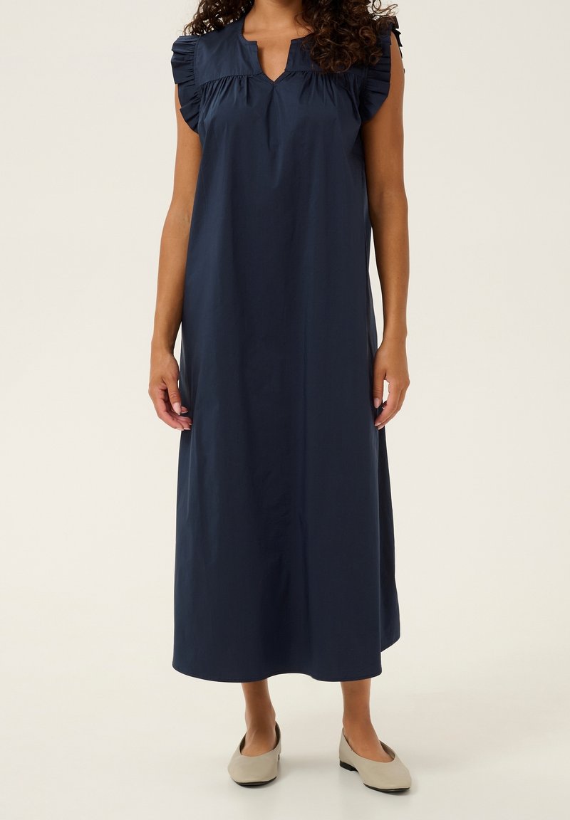 Marinblå bomullsklänning med korta puffärmar, V-ringning och flödande A-linjeformad siluett. Slät textur och ankellång design.