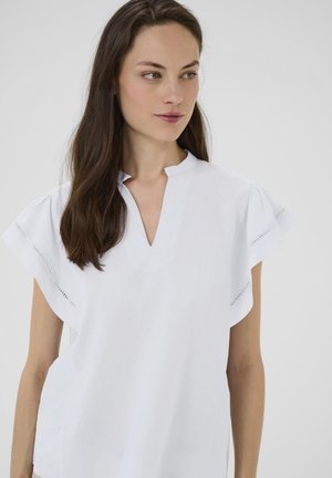 Blouse blanche à manches courtes avec un décolleté en V, ornée de coutures décoratives le long des manches. Fabriquée dans un tissu léger et lisse.