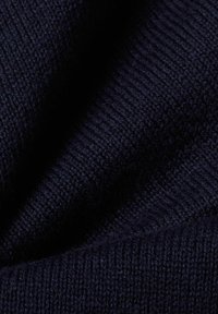 Donkerblauwe gebreide stof met een fijn ribpatroon en zachte textuur, voorzichtig gevouwen om de diepte en de kwaliteit van het materiaal te tonen.