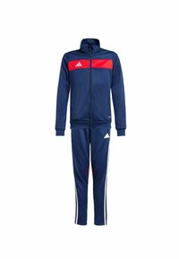Marine tracksuit met rode streep op de jas, inclusief ritsluiting en witte accentstrepen op de broek. Gemaakt van gladde stof.