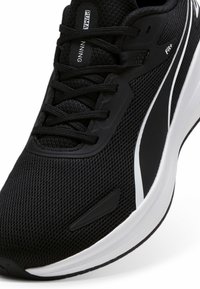 Scarpa da corsa nera con tomaia in rete, chiusura con lacci e colletto imbottito. Presenta un accento bianco e suola in gomma testurizzata per una maggiore aderenza.